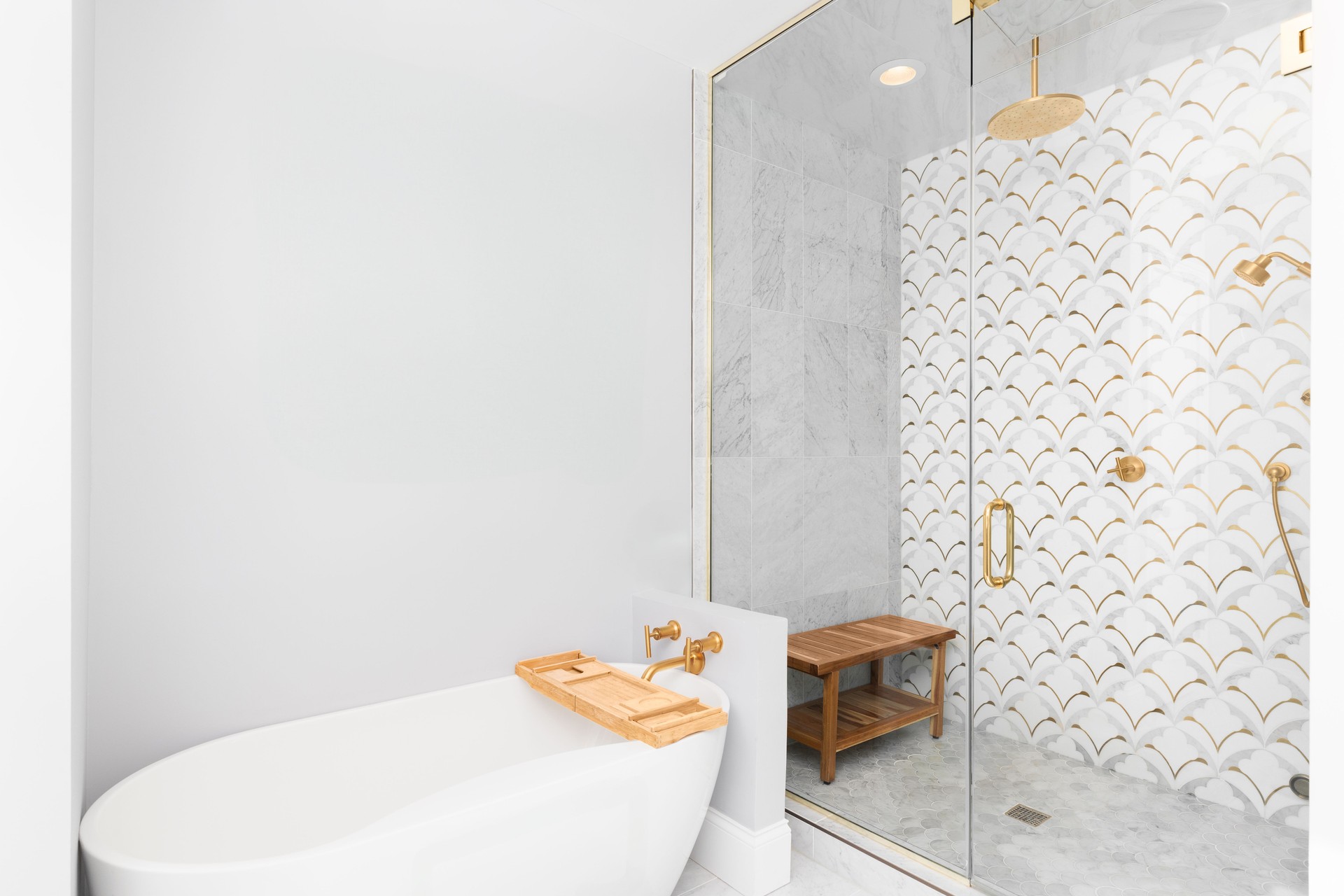 A bathroom's soaking tub and marble and gold tiled shower.
